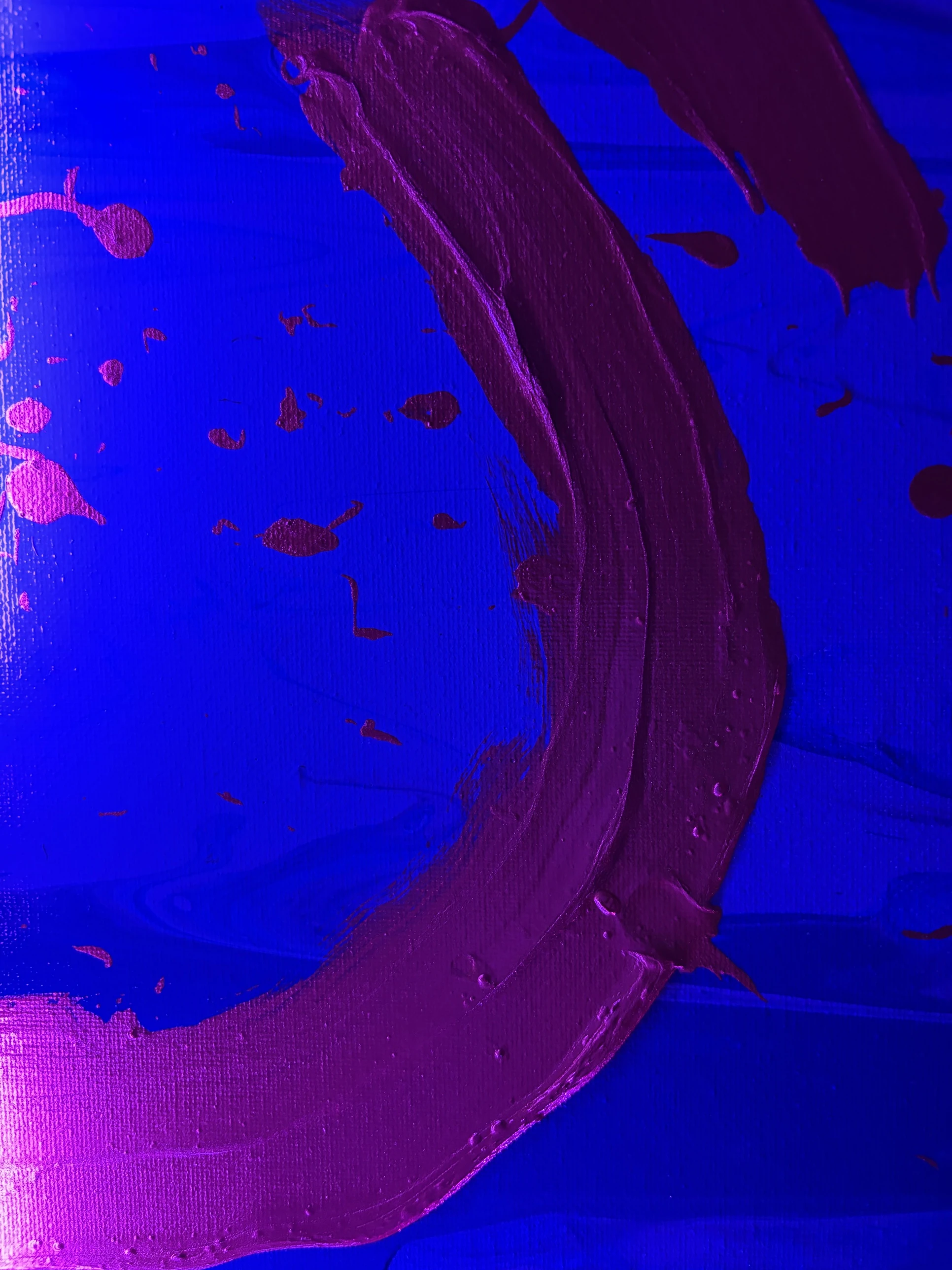 A thick curved stroke of magenta paint sweeping across an electric blue canvas, with scattered splatters
