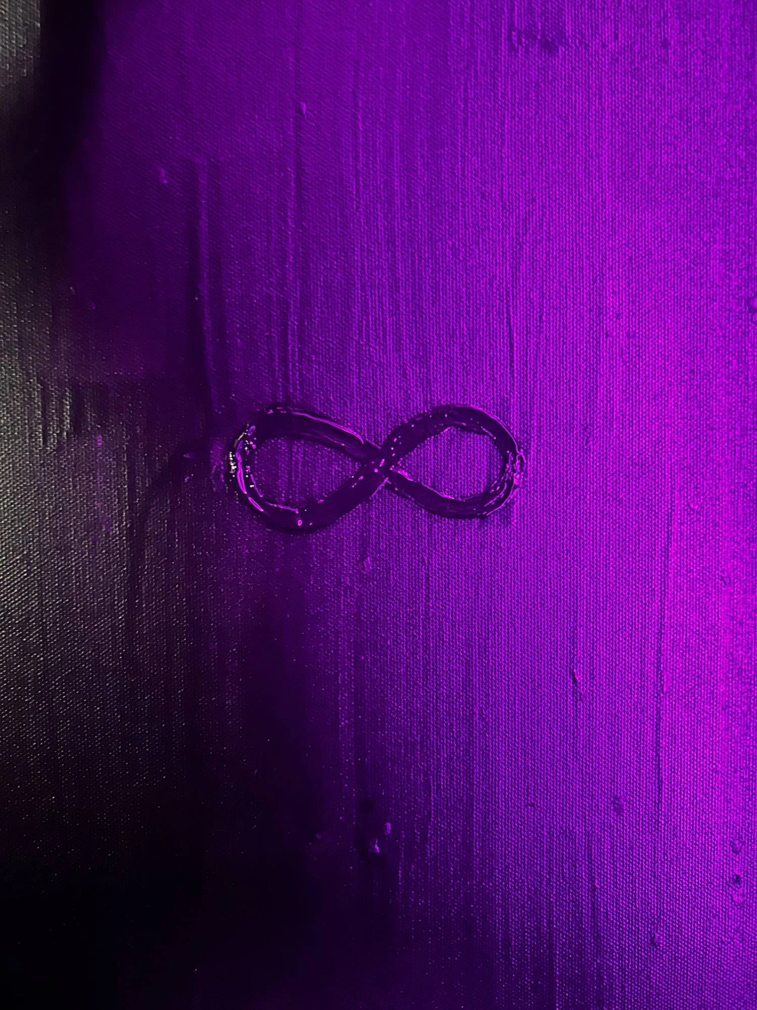 A small infinity symbol painted on a violet and magenta canvas