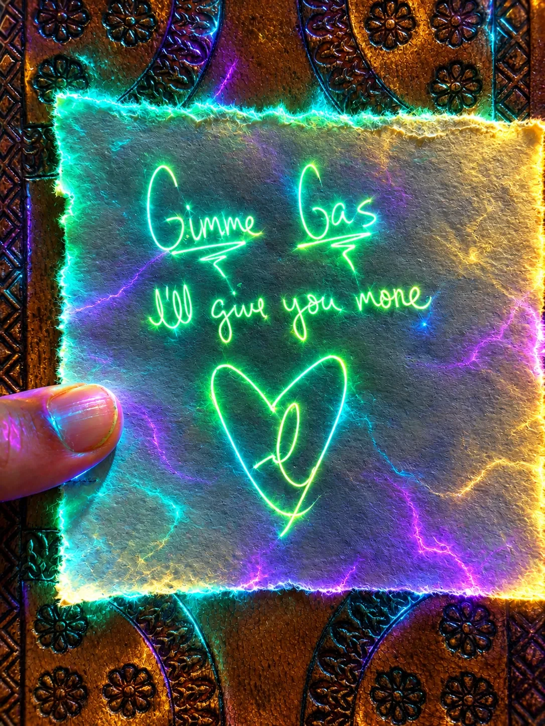 A handwritten note glowing in neon green light that reads: Gimme gas, I'll give you more, with a heart